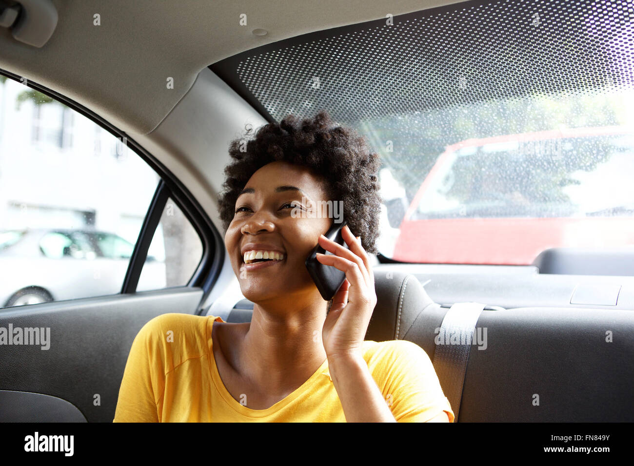 Closeup portrait of smiling young woman sitting in a car talking on mobile phone Banque D'Images