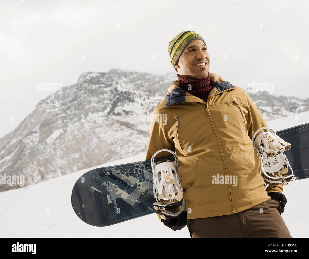 Un homme dans les montagnes portant un snowboard. Banque D'Images