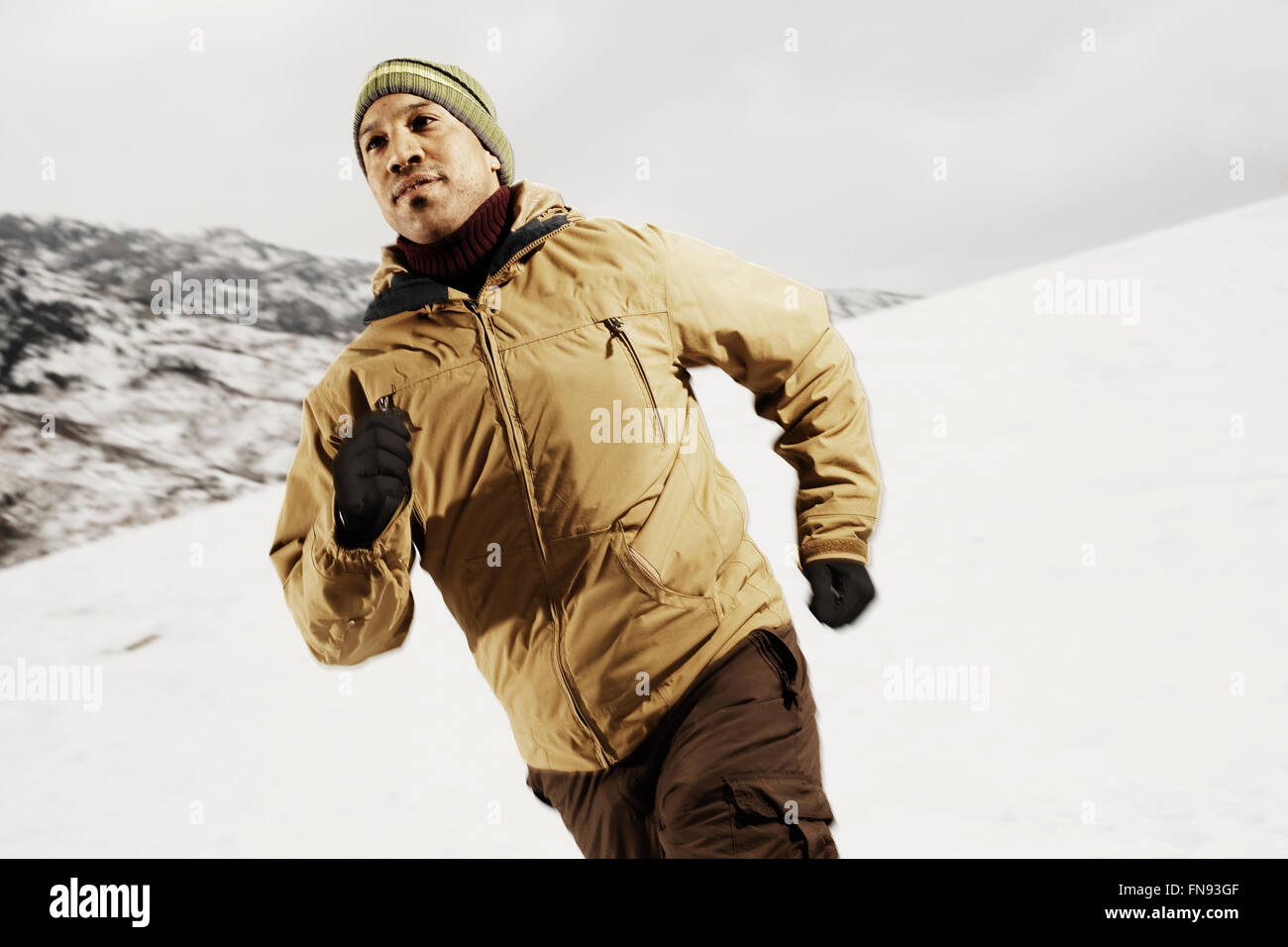 Un homme court à travers la neige dans les montagnes. Banque D'Images