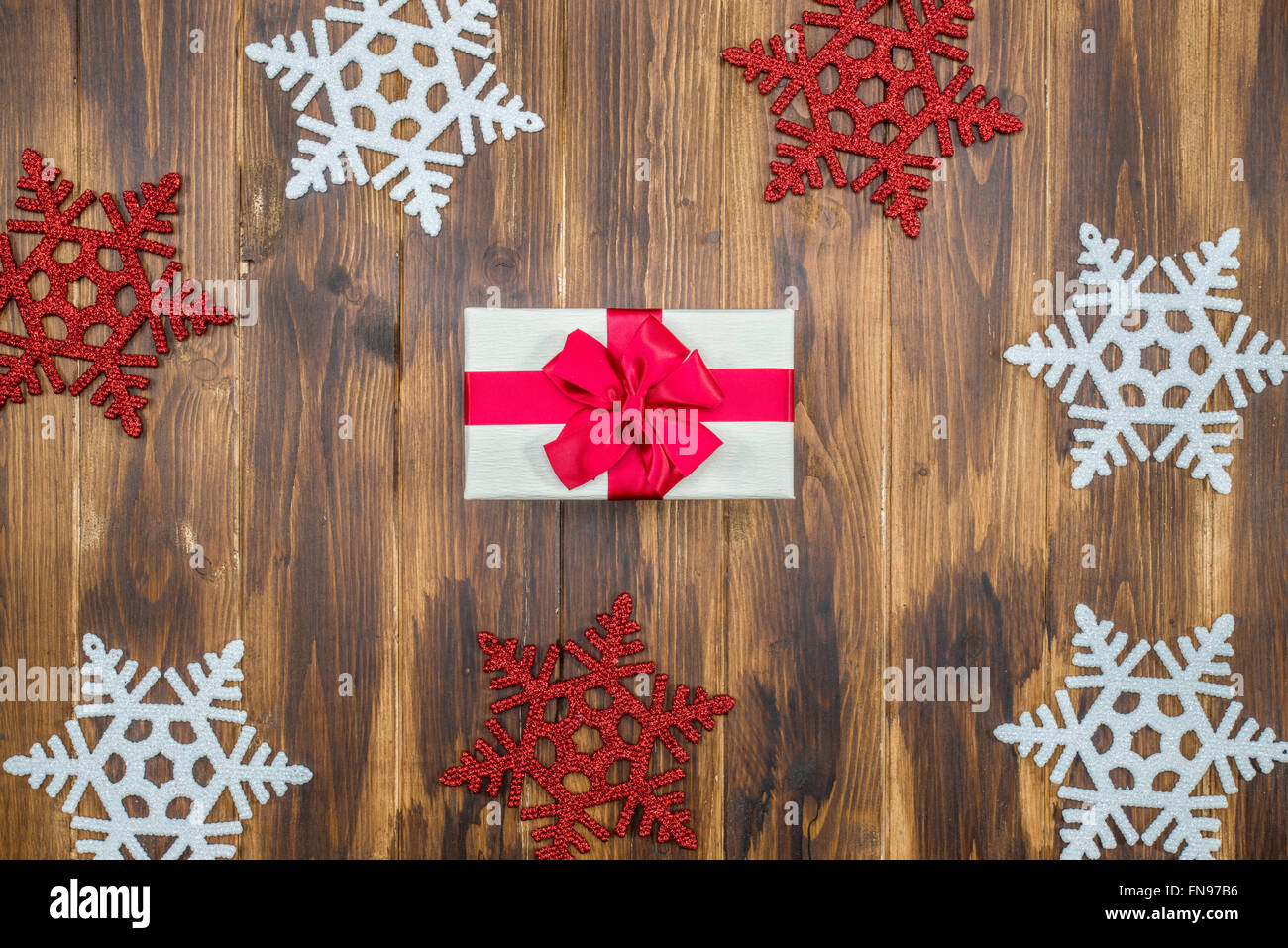 Cadeau blanc soie rouge pour maison de vacances événement avec flocon de neige sur fond de bois Banque D'Images