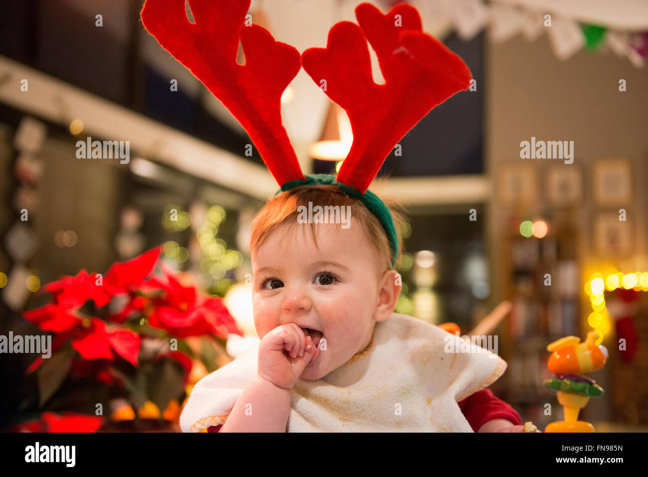 Une famille à la maison le jour de Noël. Une baby girl wearing a estimé des bois. Banque D'Images