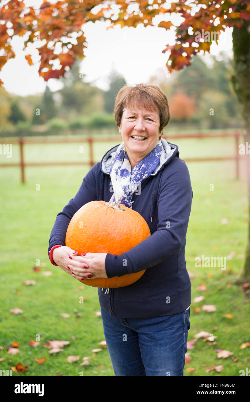 Une femme à l'extérieur tenant un grand orange citrouille. Banque D'Images