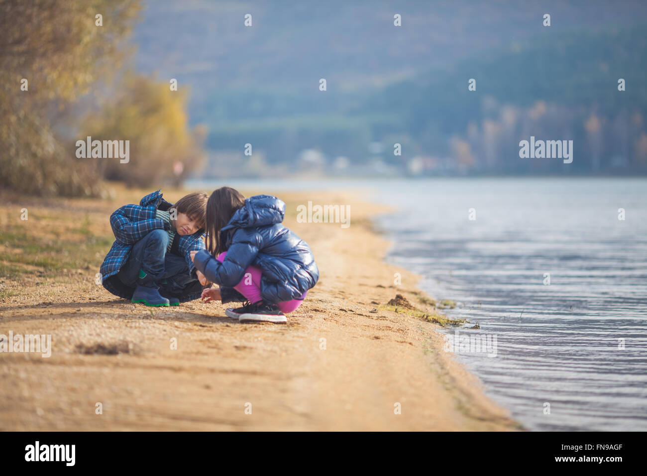 Garçon et fille jouant au bord d'un lac Banque D'Images