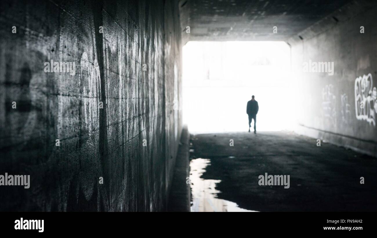 Silhouette d'un homme marchant à travers un tunnel Banque D'Images