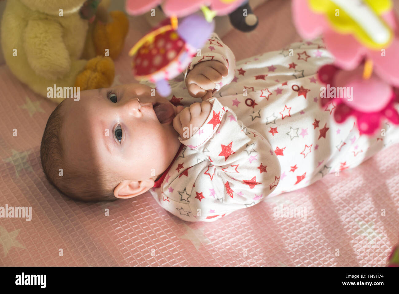 Girl lying dans lit bébé avec des jouets Banque D'Images