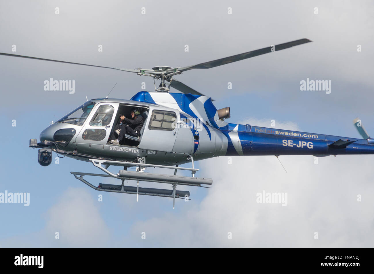 Un hélicoptère bleu et l'argent dans le ciel et prendre des photo avec l'appareil photo Banque D'Images