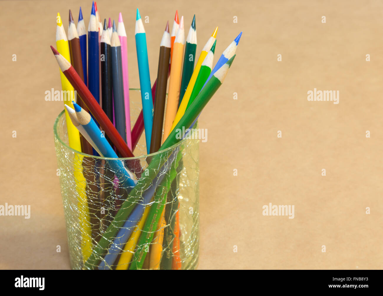 Crayon de couleur situé dans un récipient en verre sur du papier craft. Banque D'Images