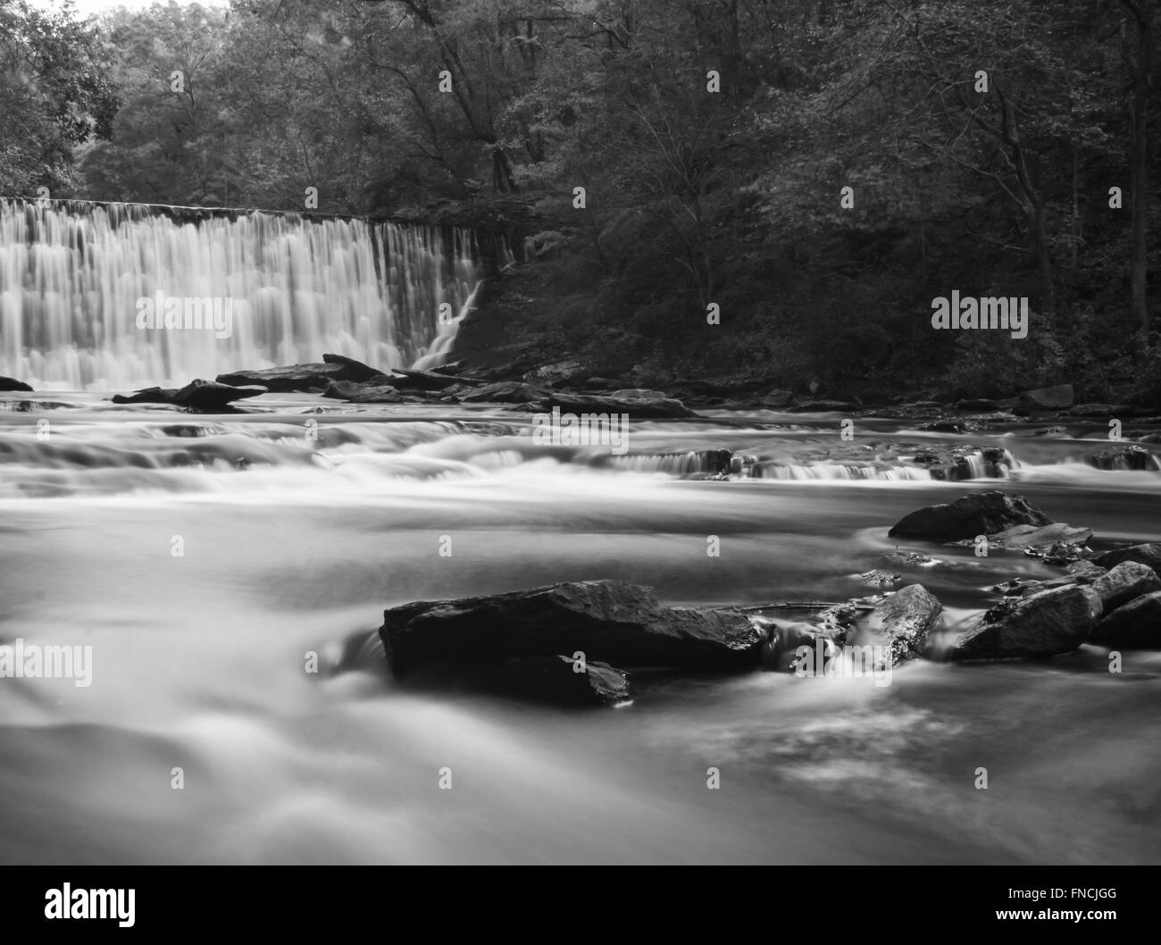 Lent doux ruisseau en aval d'un barrage tourné avec une longue exposition Banque D'Images