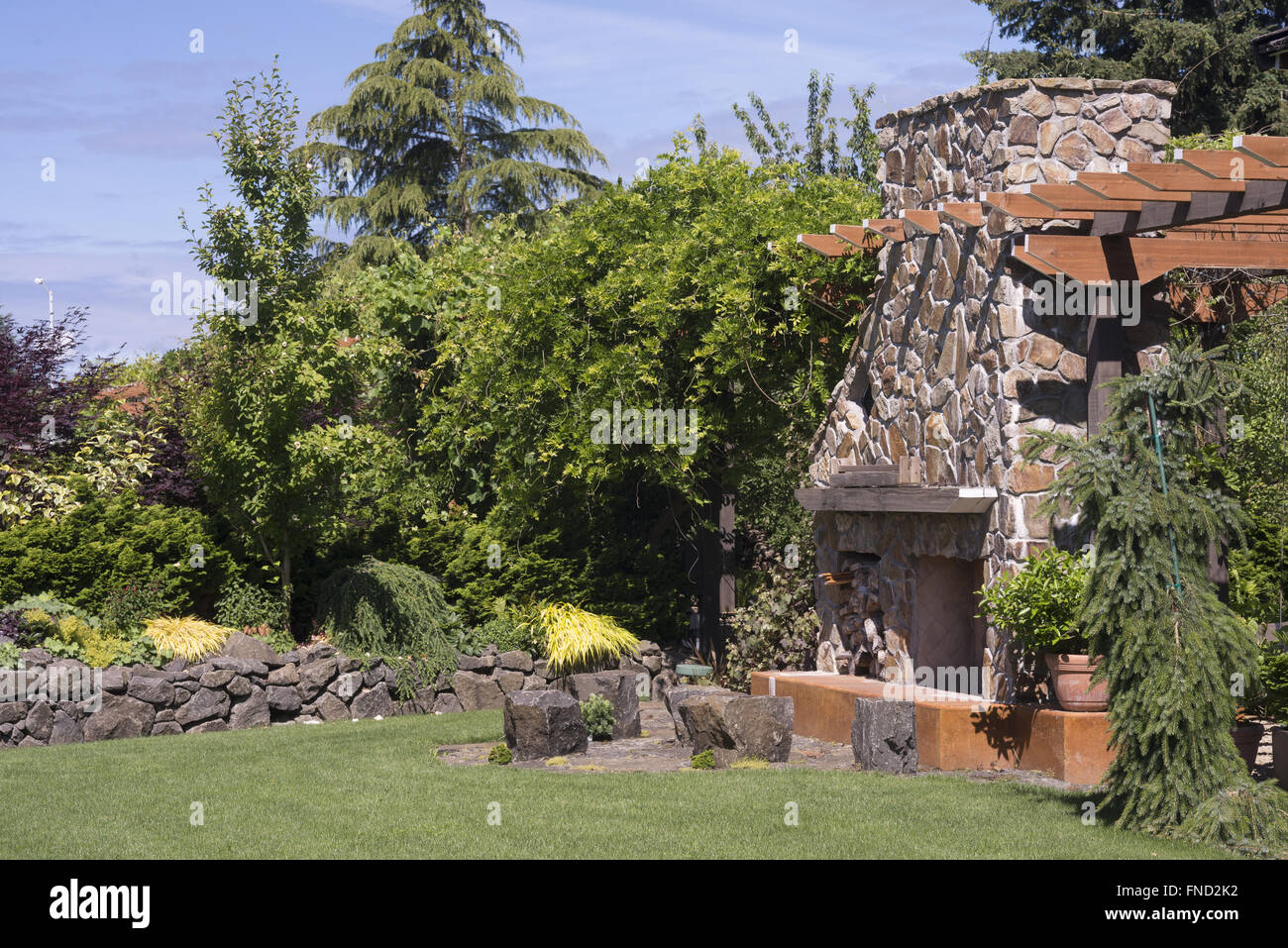 Une énorme cheminée avec pierres assis en face d'elle dans un beau jardin bien entretenu, avec un mur en pierre sèche dans le backgroun Banque D'Images
