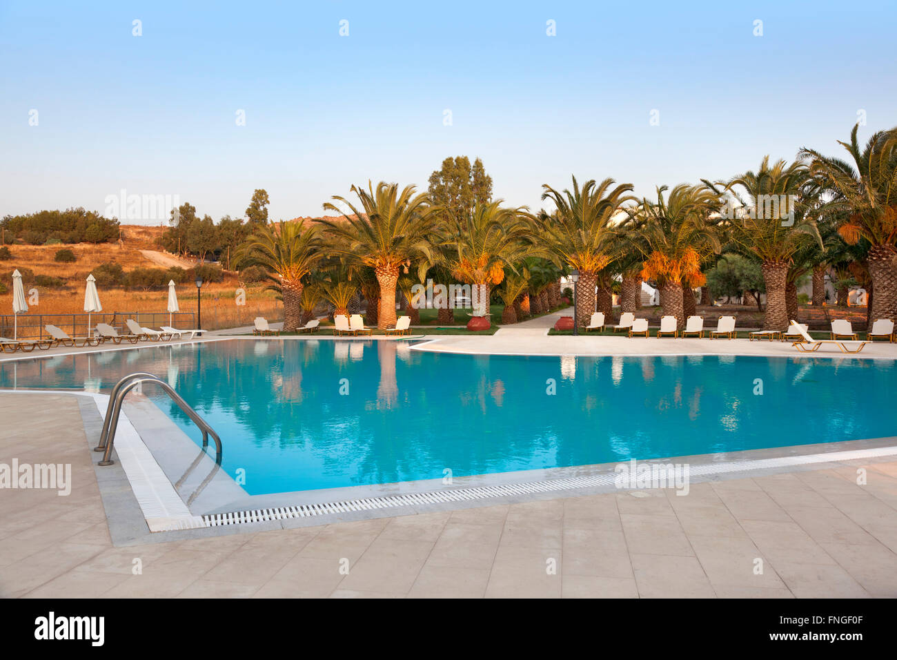 Piscine vide avec palmiers au coucher du soleil Banque D'Images