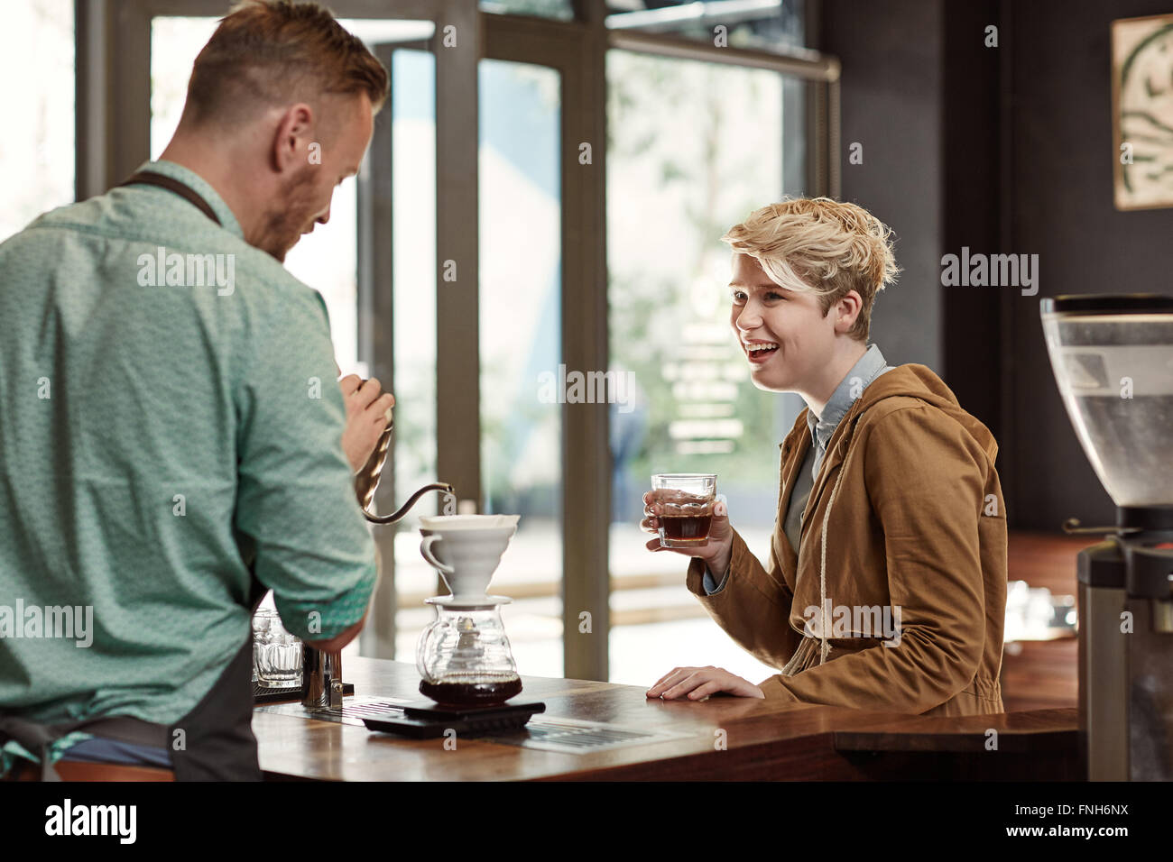 Friendly femme en riant avec un café moderne de barista Banque D'Images