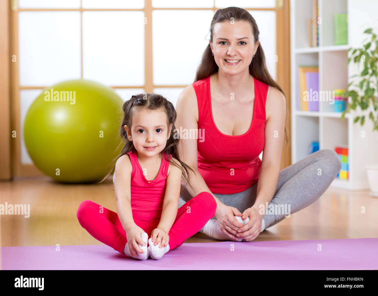 Jeune maman avec petite fille de l'exercice dans la salle de sport à la maison Banque D'Images