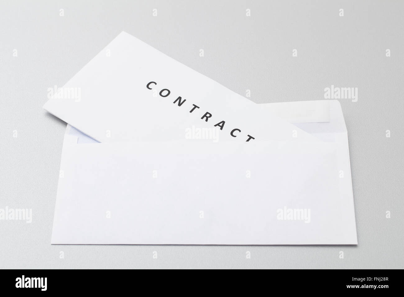 Feuilles blanches pliées avec contrat mis en enveloppe blanche vierge, prête pour l'envoi par la poste isolé sur fond. Banque D'Images