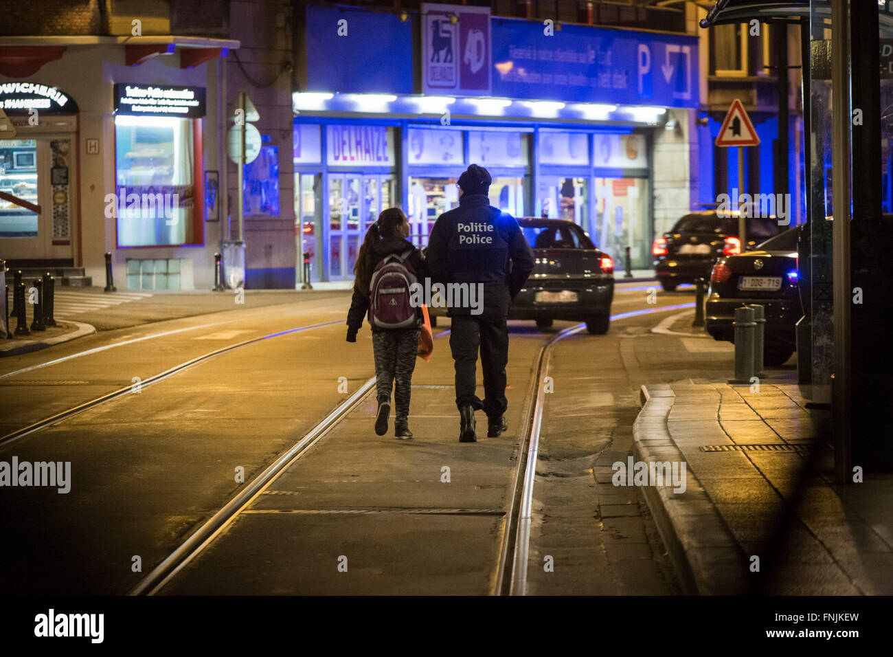 Bruxelles, Belgique. Mar 15, 2016. Un officier prend une fille retour à l'accueil après avoir permis à certaines personnes de retourner dans leurs maisons. Représentants de Bruxelles a confirmé une opération majeure est en cours impliquant la police enquête sur les 13 tirs novembre lorsqu'au moins un homme armé a ouvert le feu, bien que les médias locaux ont rapporté la chasse à l'homme qui a suivi comme impliquant deux suspects. Credit : Aurore Belot/Pacific Press/Alamy Live News Banque D'Images