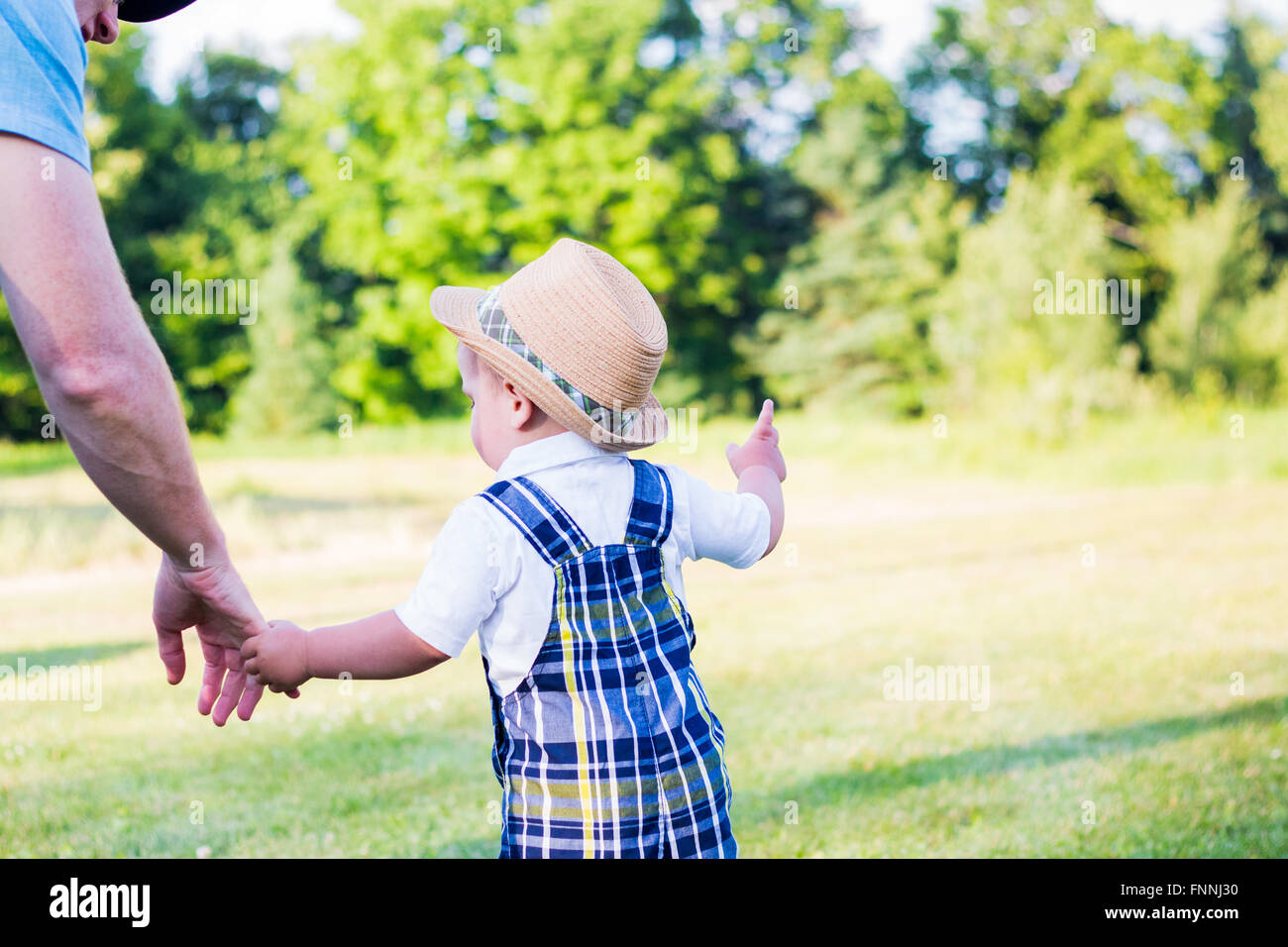 Petit garçon enfant plaid dans une combinaison et un chapeau de paille qui  tient la main de son oncle, le conduisant à explorer le domaine Photo Stock  - Alamy