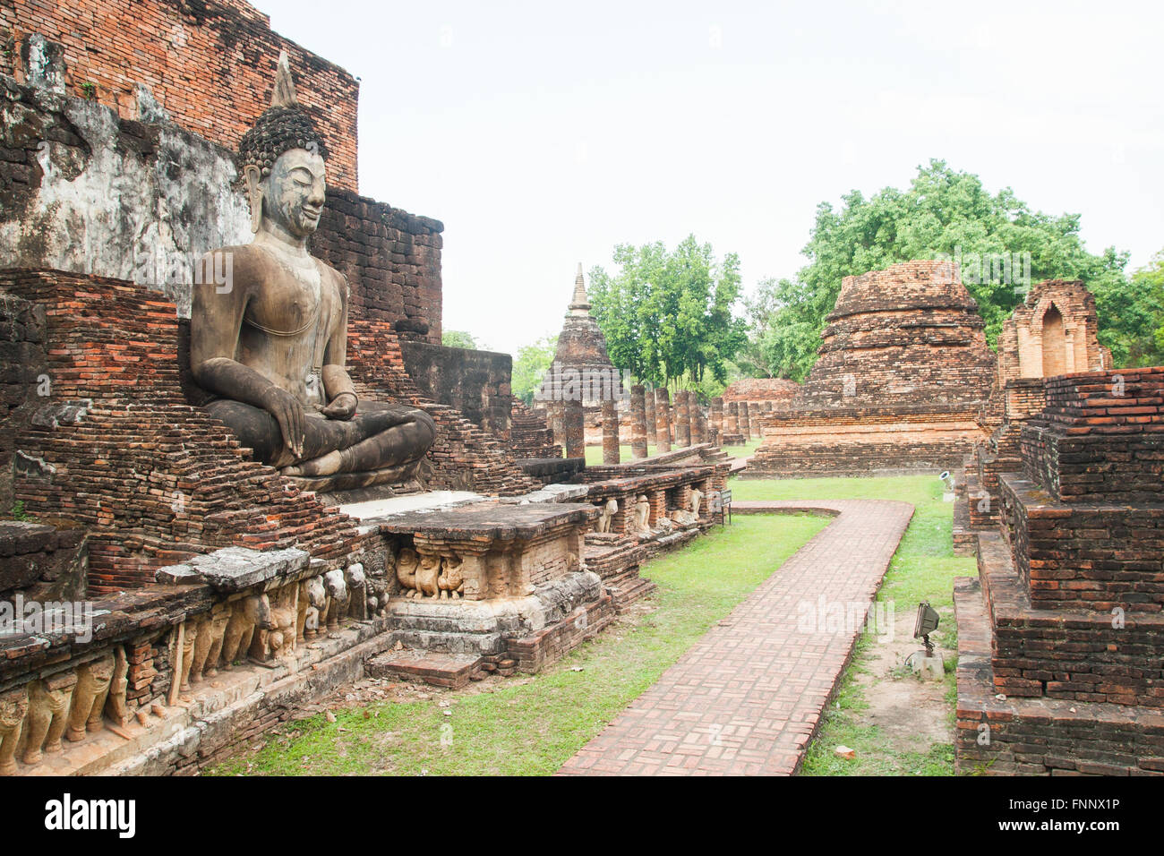 Sculpture Bouddha assis parmi les ruines en parc historique de Sukhothai, Thaïlande Banque D'Images