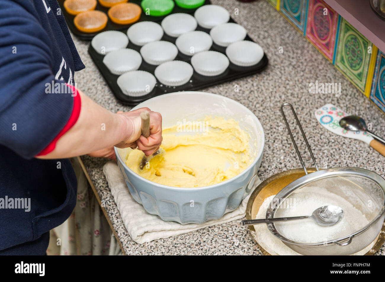 Une femme fusionne les ingrédients pour faire des gâteaux de tasse dans une cuisine maison. Banque D'Images