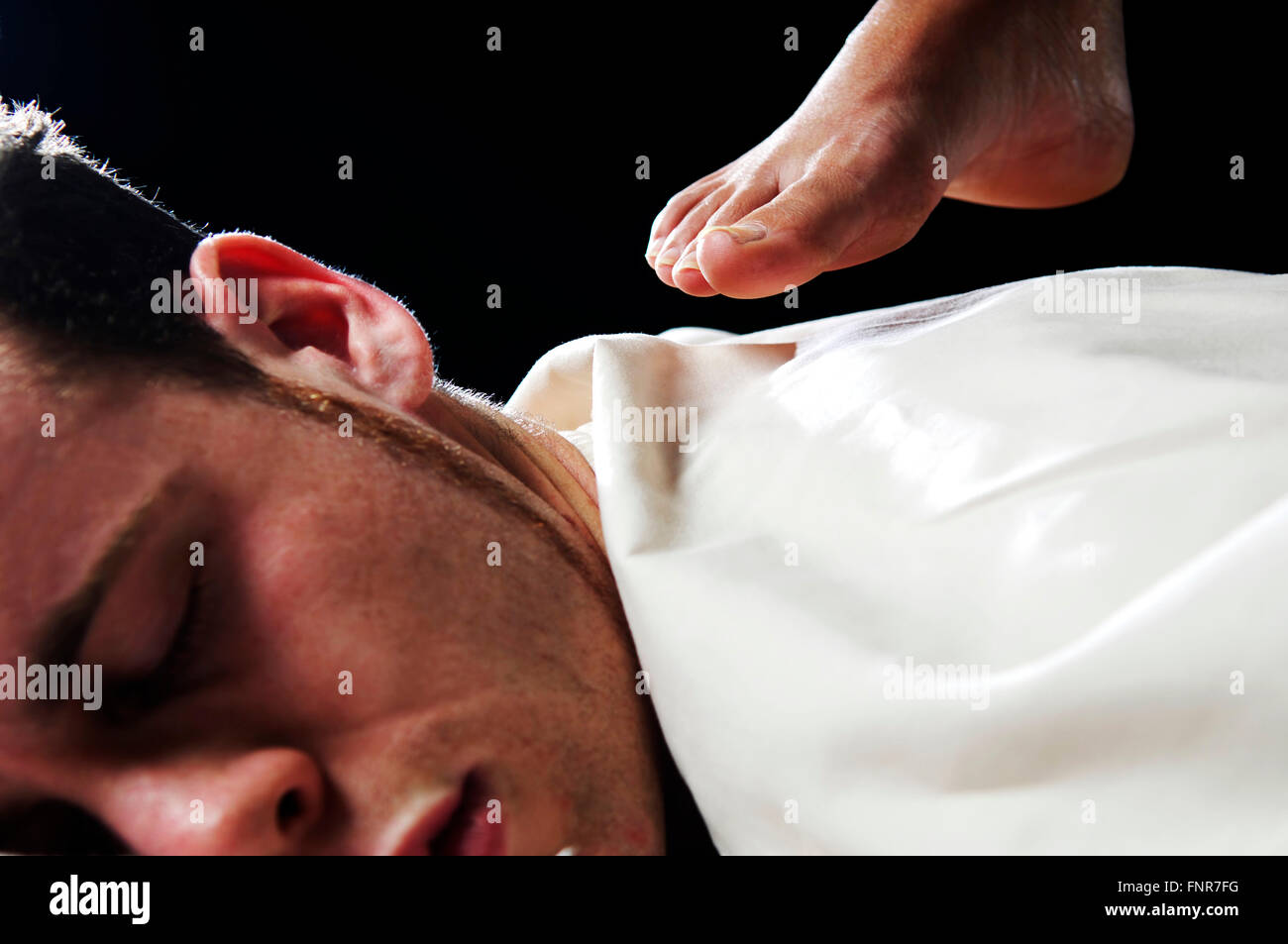 Un jeune homme recevant un massage du dos en profondeur des tissus aux pieds nus. Banque D'Images