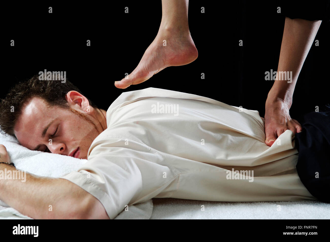 Un jeune homme recevant un massage du dos aux pieds nus des tissus en profondeur. Banque D'Images