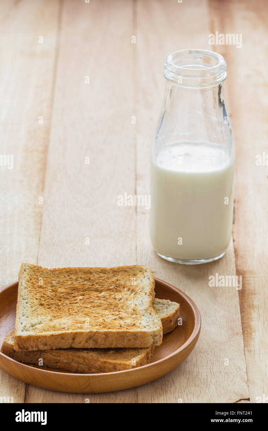 Toast en plaque en bois avec une bouteille de lait sur la table en bois Banque D'Images