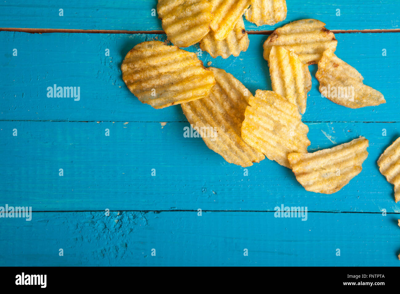 Croustilles de pommes de terre éparpillées sur une table en bois bleu Banque D'Images