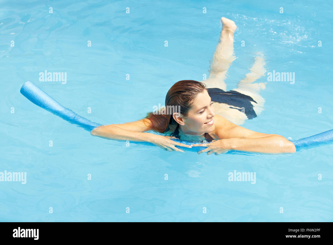 Jolie femme natation apprentissage avec nager en piscine de nouilles Banque D'Images