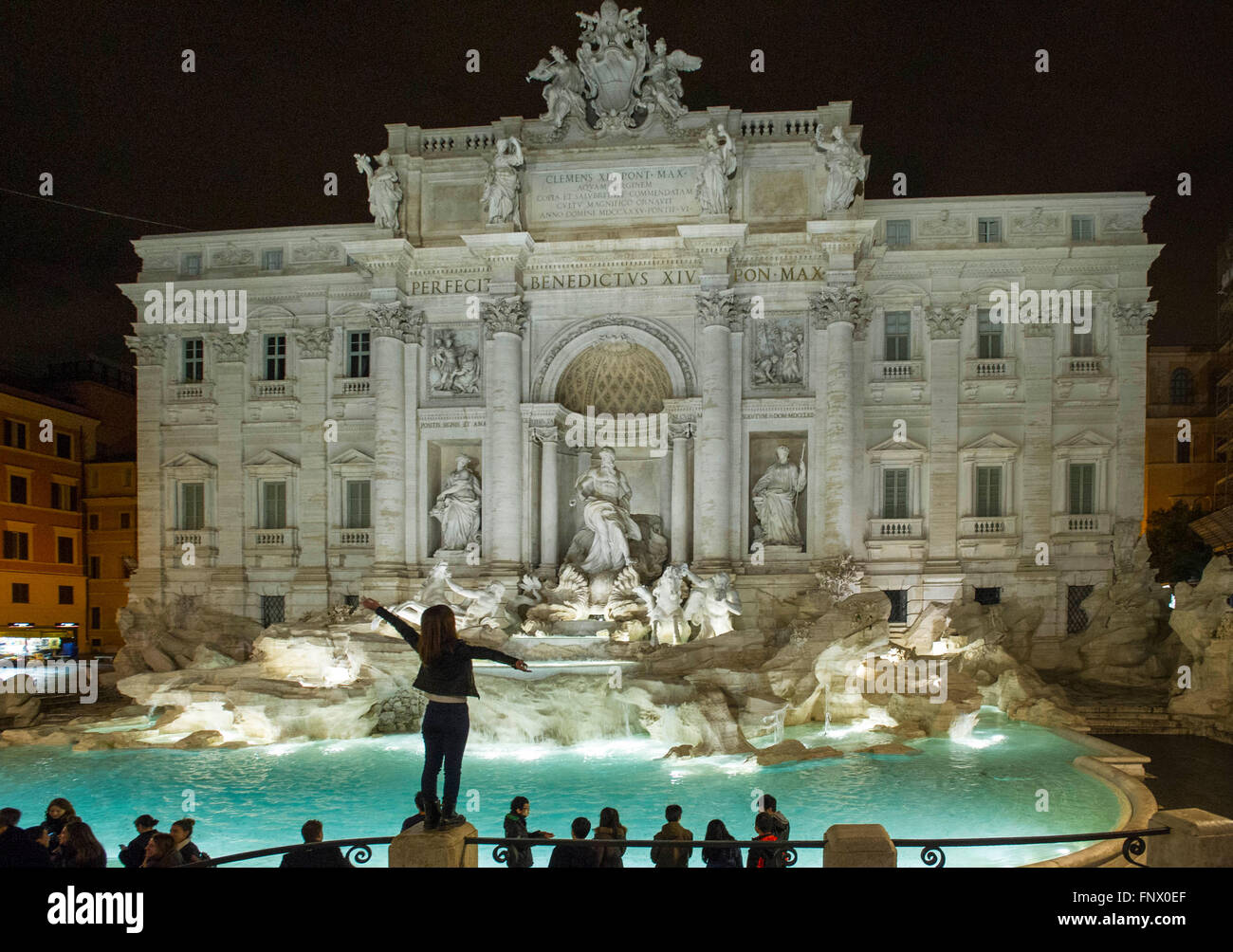 29/02/2016. La fontaine de Trevi, Rome, Italie la nuit avec les touristes. Une jeune femme se tient sur un pilier à la Fontaine de Trevi Banque D'Images