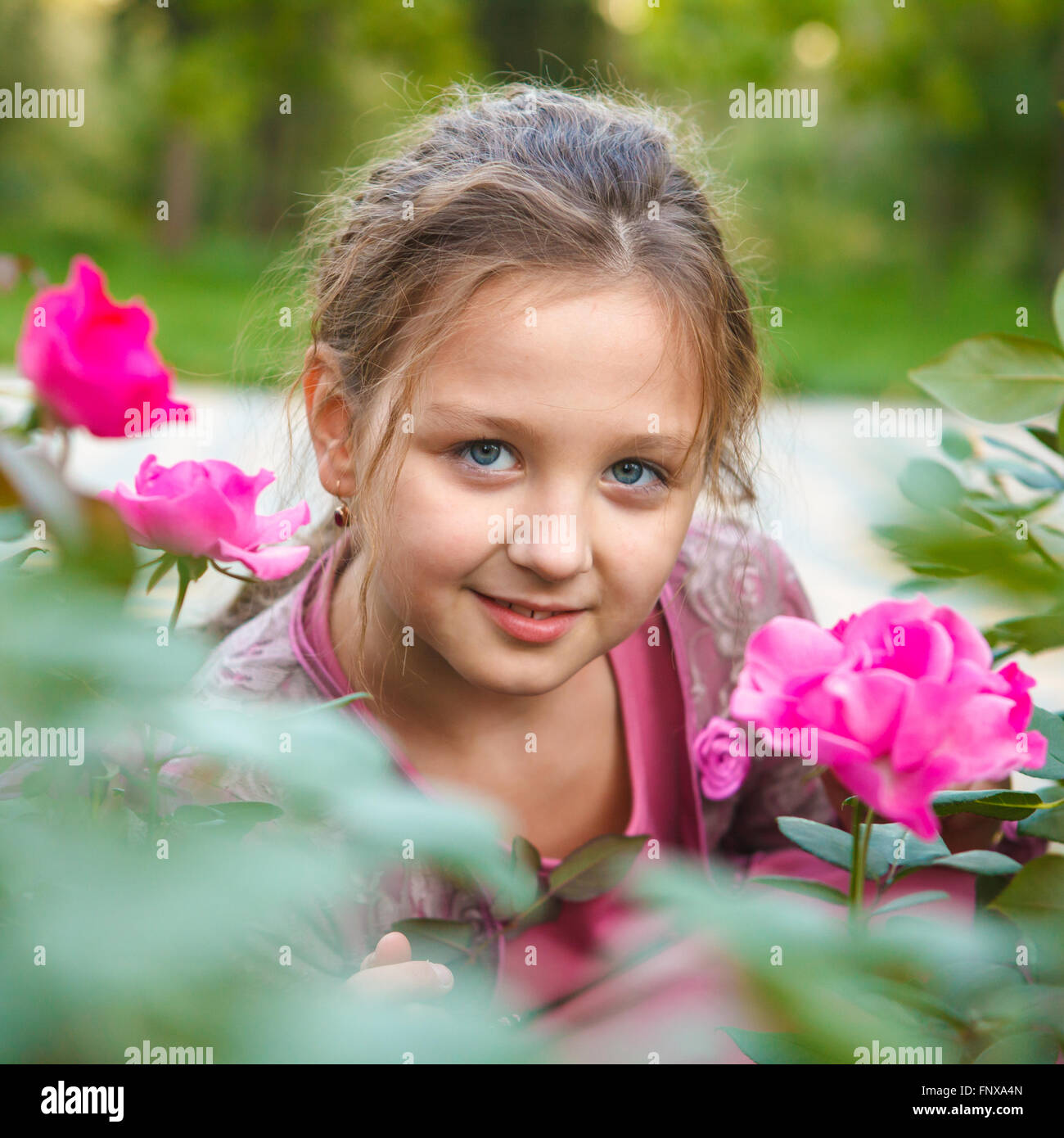 Portrait d'une jeune fille dans un buisson rose dans le parc Banque D'Images