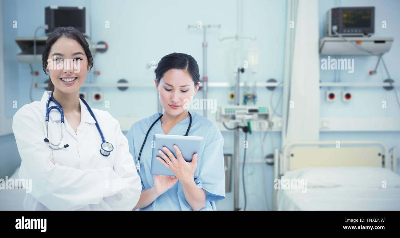 Image composite de chirurgien using digital tablet with group around table in hospital Banque D'Images