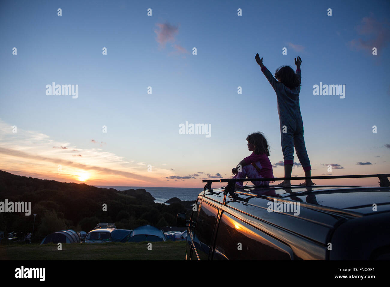 Deux jeunes enfants regarder le coucher du soleil sur un camping. Les souvenirs d'enfance sont faites sur des vacances en camping au bord de la mer en été. Banque D'Images