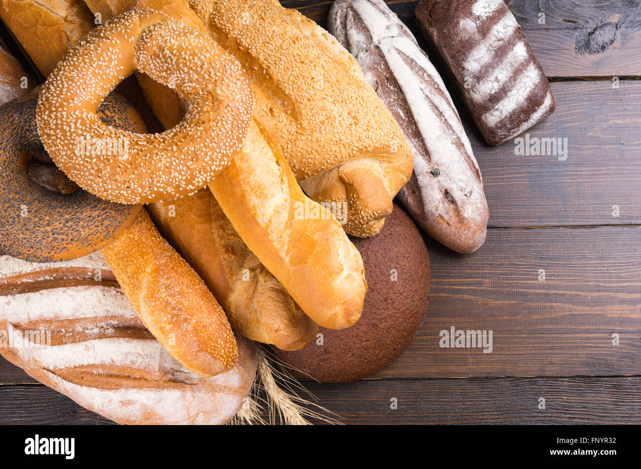 Grand assortiment de pains mixte composé de graines de pavot et de sésame, bagels, baguettes de pain français, rouleaux et le seigle sur table en bois Banque D'Images