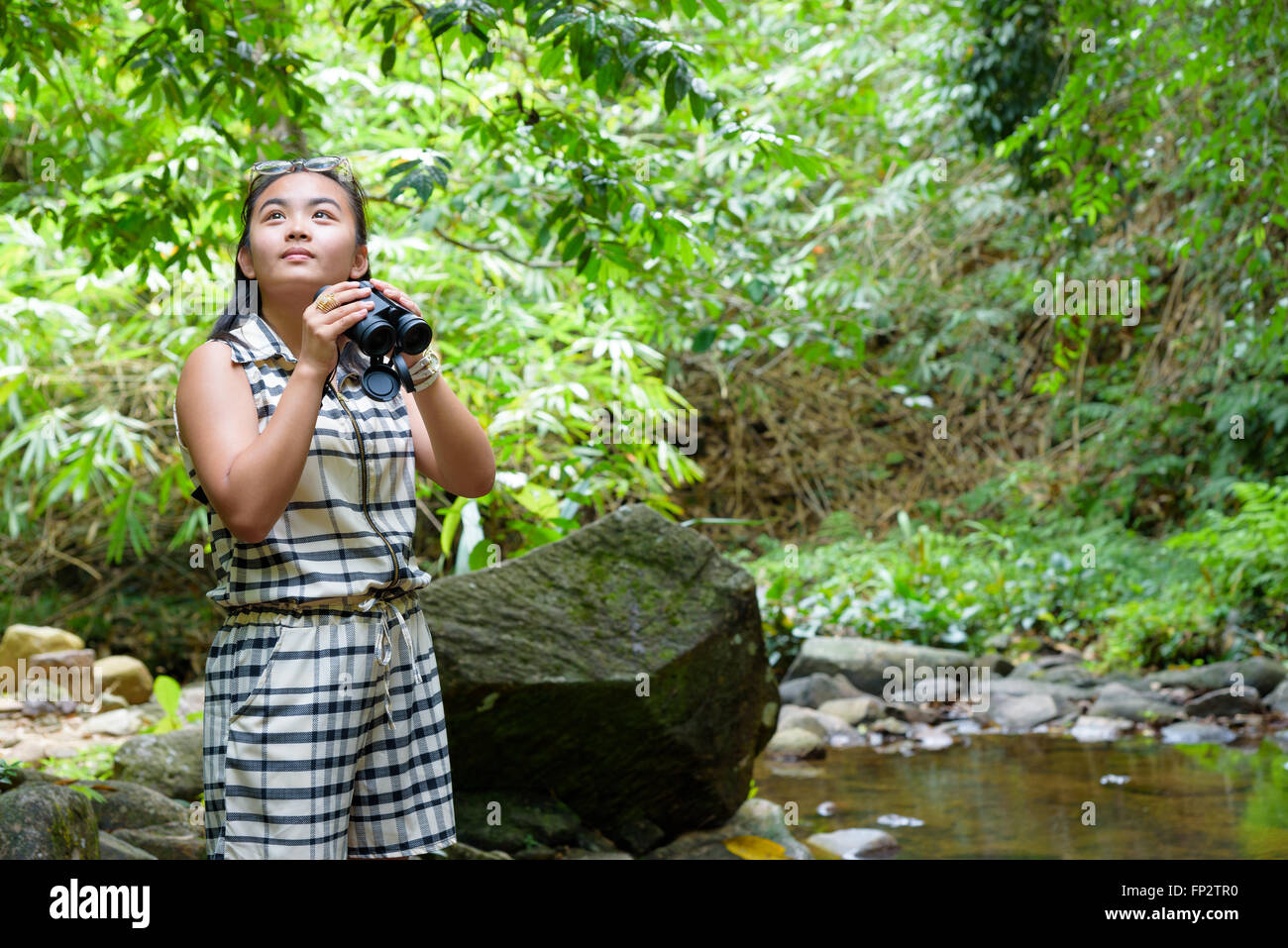 Belle jeune fille randonnées est à l'aide de jumelles pour regarder les oiseaux dans la forêt tropicale près de la cascade en Thaïlande Banque D'Images