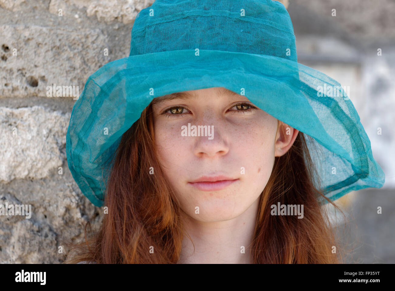 Fille aux cheveux roux avec un chapeau de soleil turquoise à sérieusement, portrait, Italie Banque D'Images