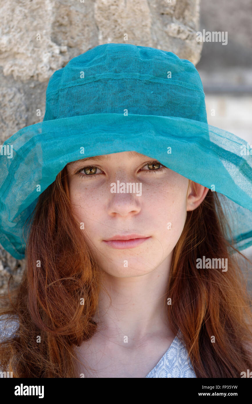 Fille aux cheveux roux avec un chapeau de soleil turquoise à sérieusement, portrait, Italie Banque D'Images