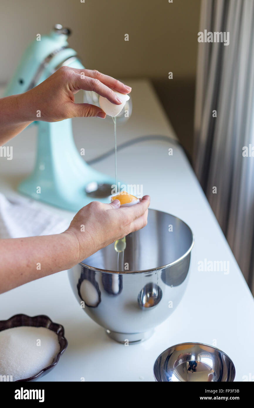 Fissuration femme un oeuf dans un bol, séparer le blanc d'oeuf de l'oeuf Banque D'Images