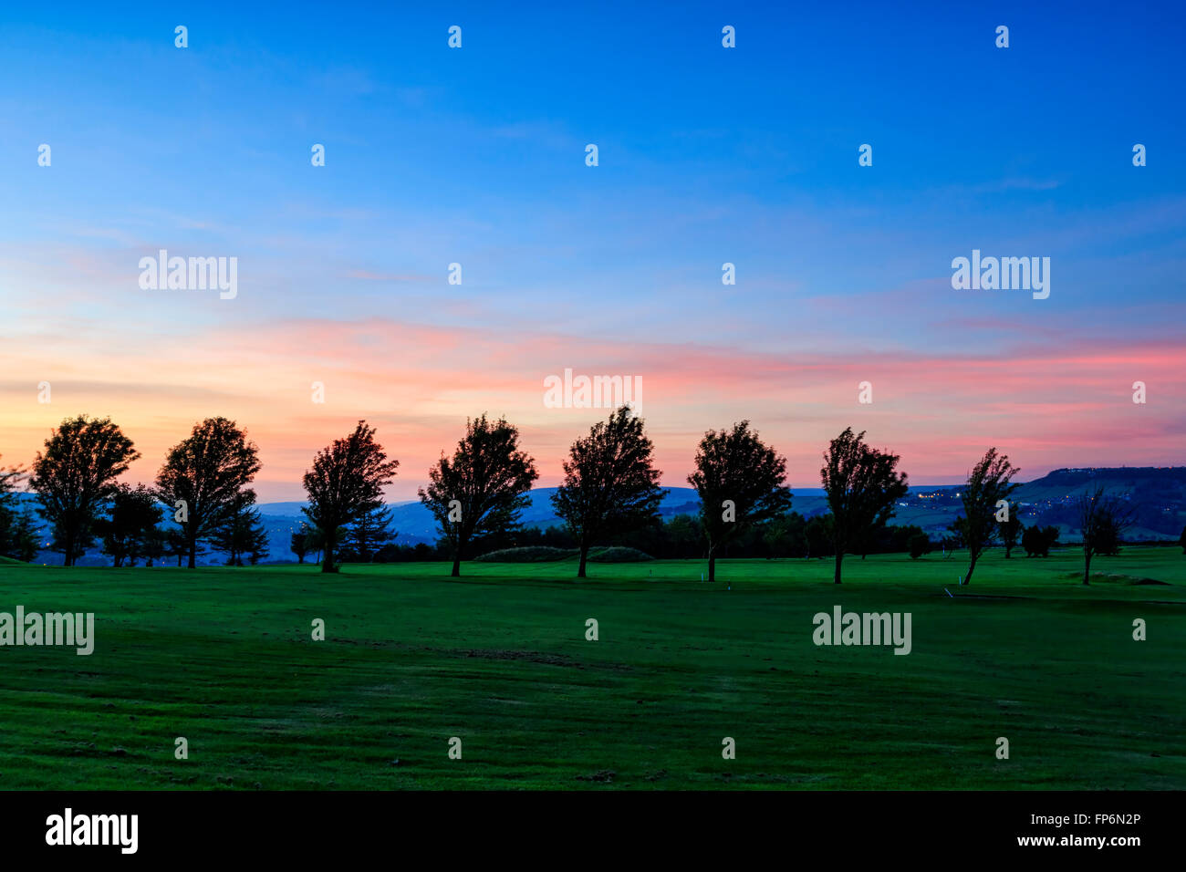 Coucher du soleil avec une rangée d'arbres sur un terrain de golf Banque D'Images