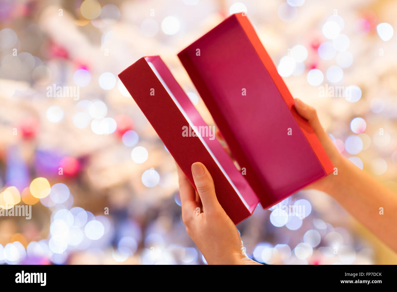 Femme ouvre un cadeau rouge en face d'un arbre de Noël Banque D'Images