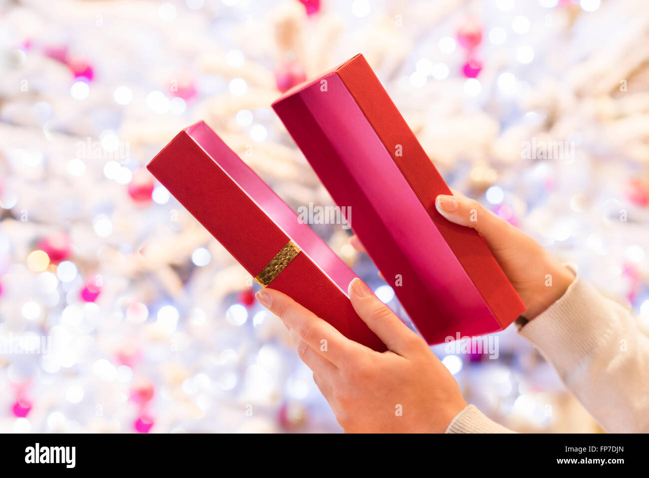 Femme ouvre un cadeau rouge en face d'un arbre de Noël Banque D'Images