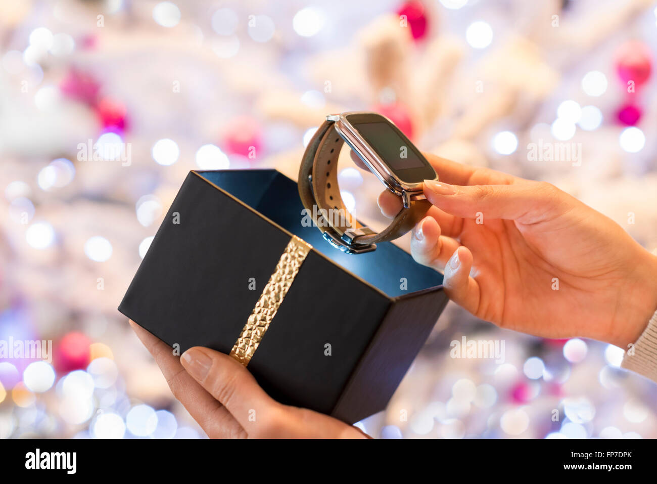 Femme découvre une smartwatch en cadeau de Noël. Arrière-plan de l'arbre de Noël Boke Banque D'Images