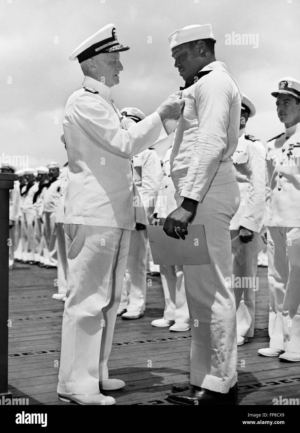 L'amiral Chester Nimitz W., commandant en chef de la Flotte du Pacifique, l'épinglage, la Croix de la Navy sur Doris 'Dorie' Miller, steward's Mate 1/c, lors d'une cérémonie à bord d'un navire de guerre de la Marine américaine à Pearl Harbor, le 27 mai 1942. Miller a obtenu la Croix de la Marine pour sa bravoure lors de l'attaque sur Pearl Harbor le 7 décembre 1941 et a été le premier noir Américain à recevoir le prix. La Marine américaine officielle Photo. Banque D'Images