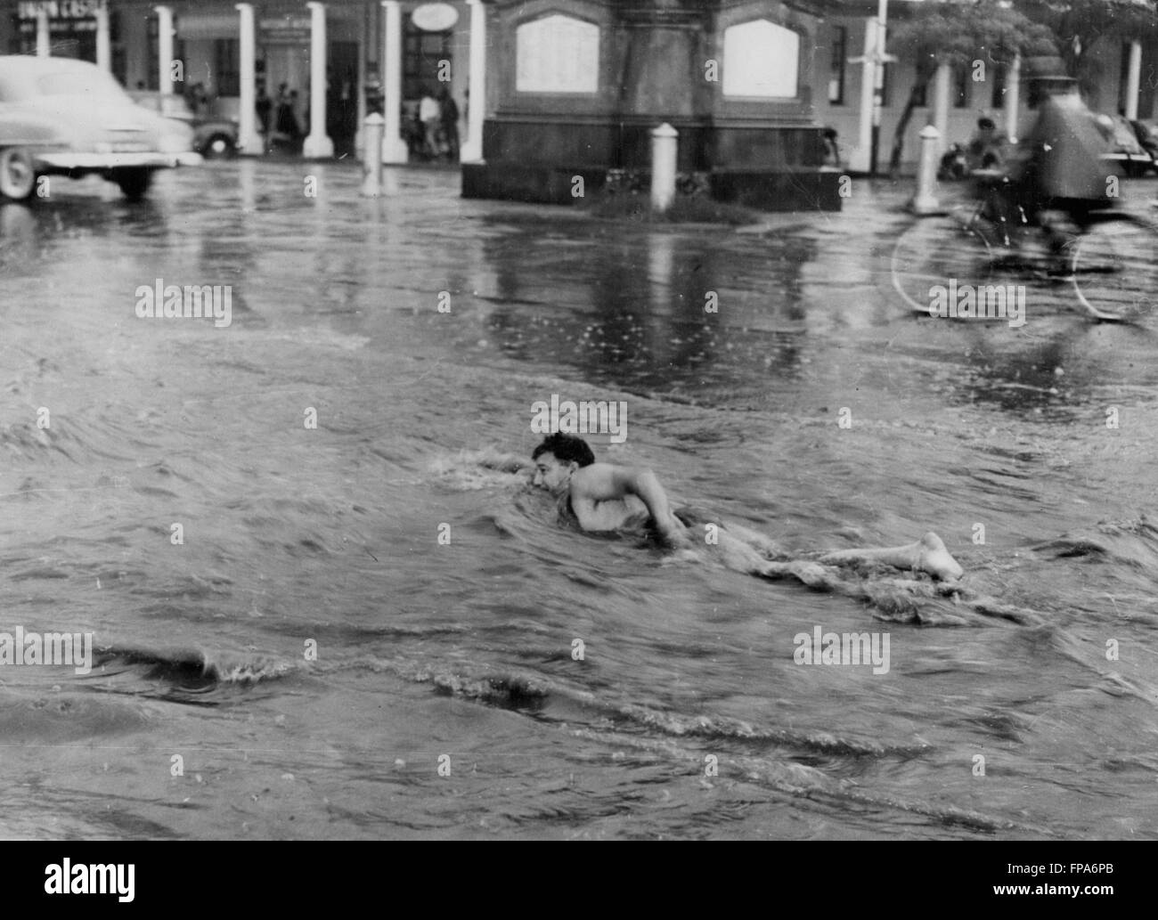 1962 - Il va nager - le long de la rue .lui .Bulawayo, quand les pluies Jeu : Bulawayo, deuxième plus grande ville de la Rhodésie Southren n'a pas d'eaux pluviales - et quand il pleut Il pleut, certes - et la masse de l'eau prend beaucoup de temps pour s'en tirer. Cet hommes est vu en profitant de la dernière tempête dans la ville, vous en nageant le long de la rue Main - que le trafic passe. © Keystone Photos USA/ZUMAPRESS.com/Alamy Live News Banque D'Images