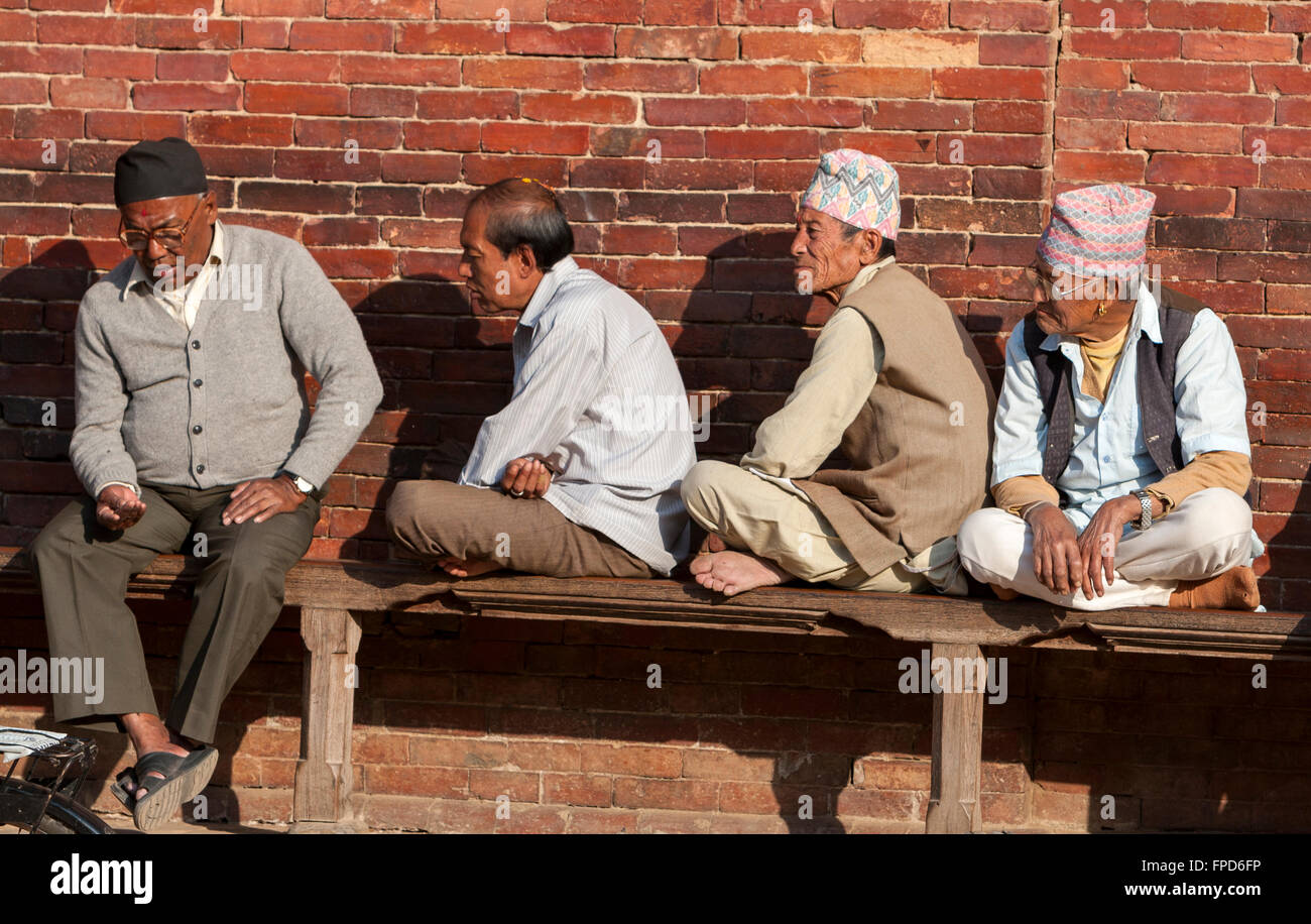 Le Népal, Patan. Quatre hommes népalais assis sur un banc à Durbar Square. Banque D'Images