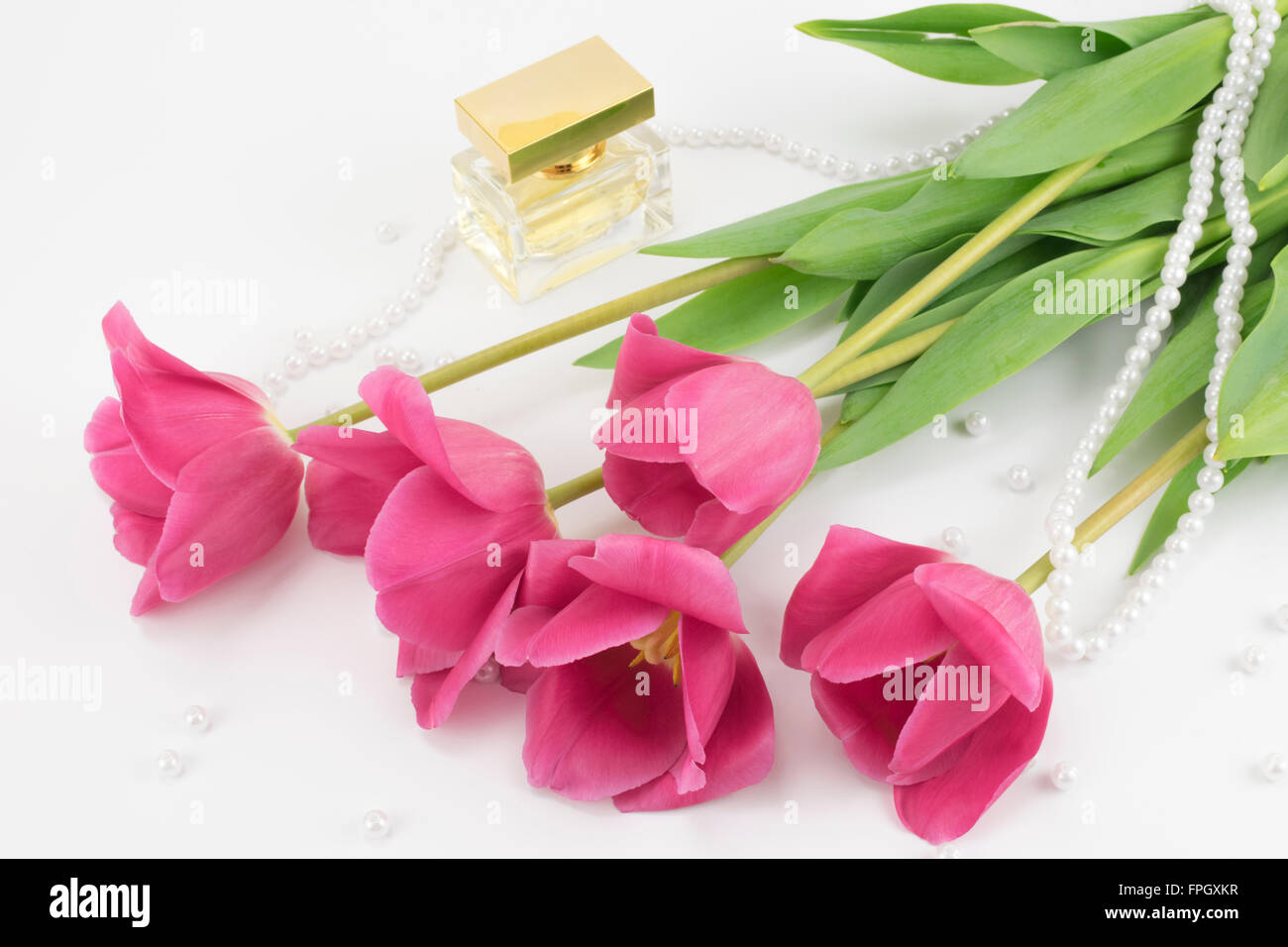 Bouquet de tulipes rouges, de parfum et de perles couché Banque D'Images