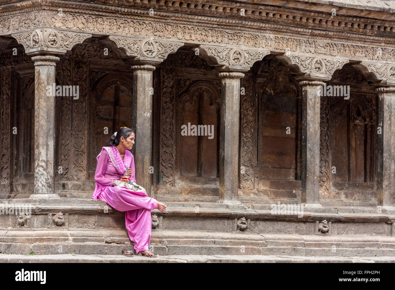 Népal, Patan. Jeune Femme Népalaise Assise Sur Le Bord Du Temple, Banque D'Images