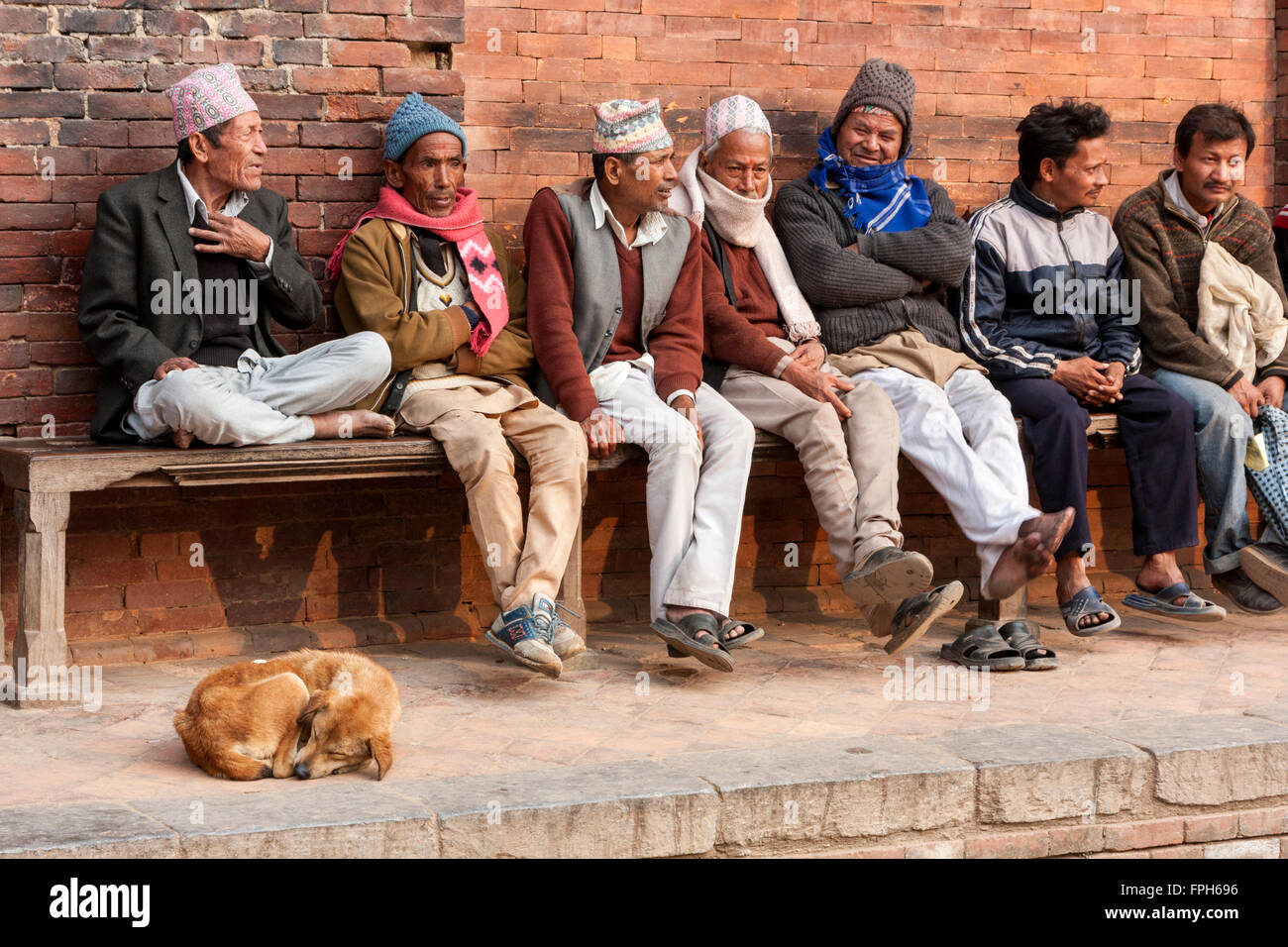 Le Népal, Patan. Les hommes portant des chapeaux traditionnels assis sur un banc, par le Palais Royal, Durbar Square. Banque D'Images