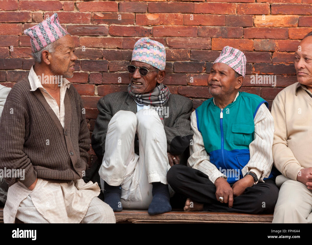 Le Népal, Patan. Les hommes portant des chapeaux traditionnels assis sur un banc, par le Palais Royal, Durbar Square. Banque D'Images