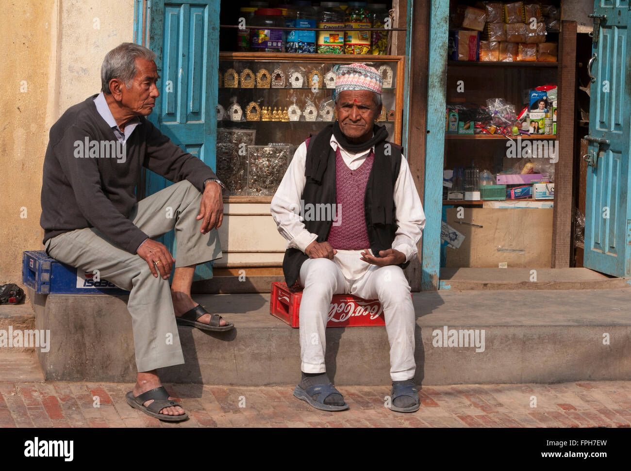 Le Népal, Patan. Deux hommes assis en face d'un magasin. Banque D'Images