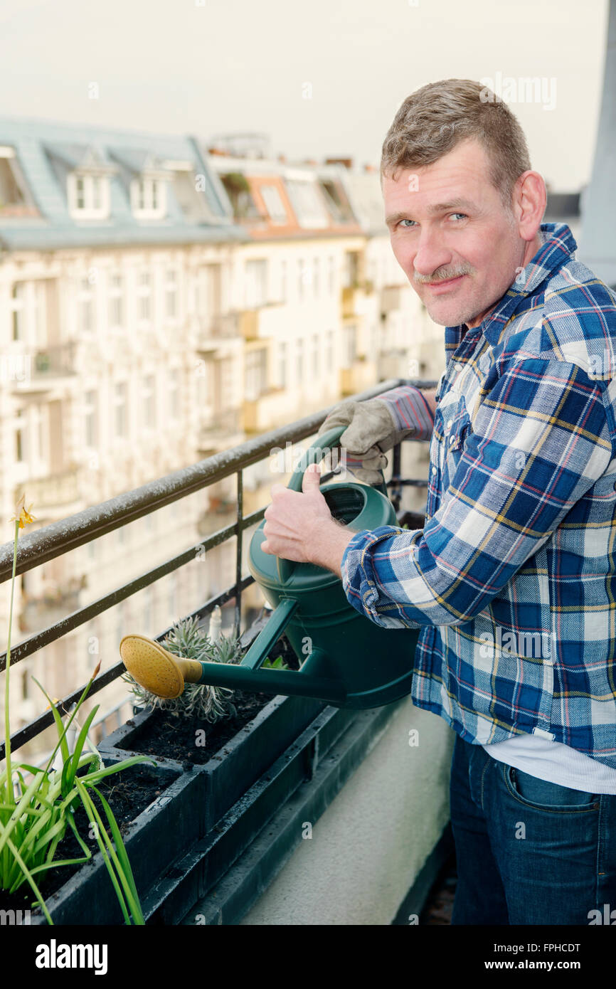 Man watering plants at balcon sur le toit Banque D'Images