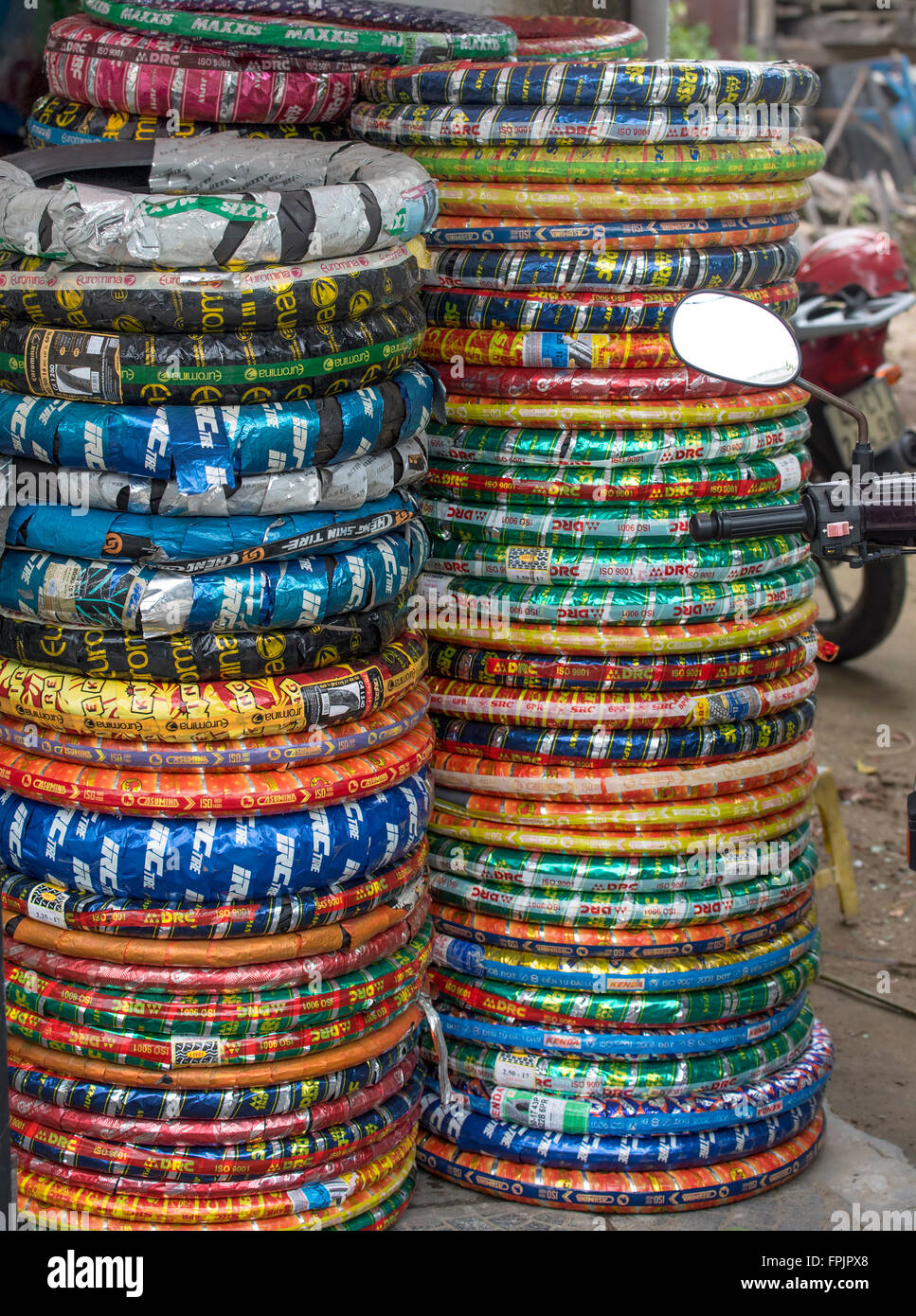 Mise sous film rétractable de couleur vive autour des pneus pour motos dans un garage à Hoi An. Vietnam, Banque D'Images