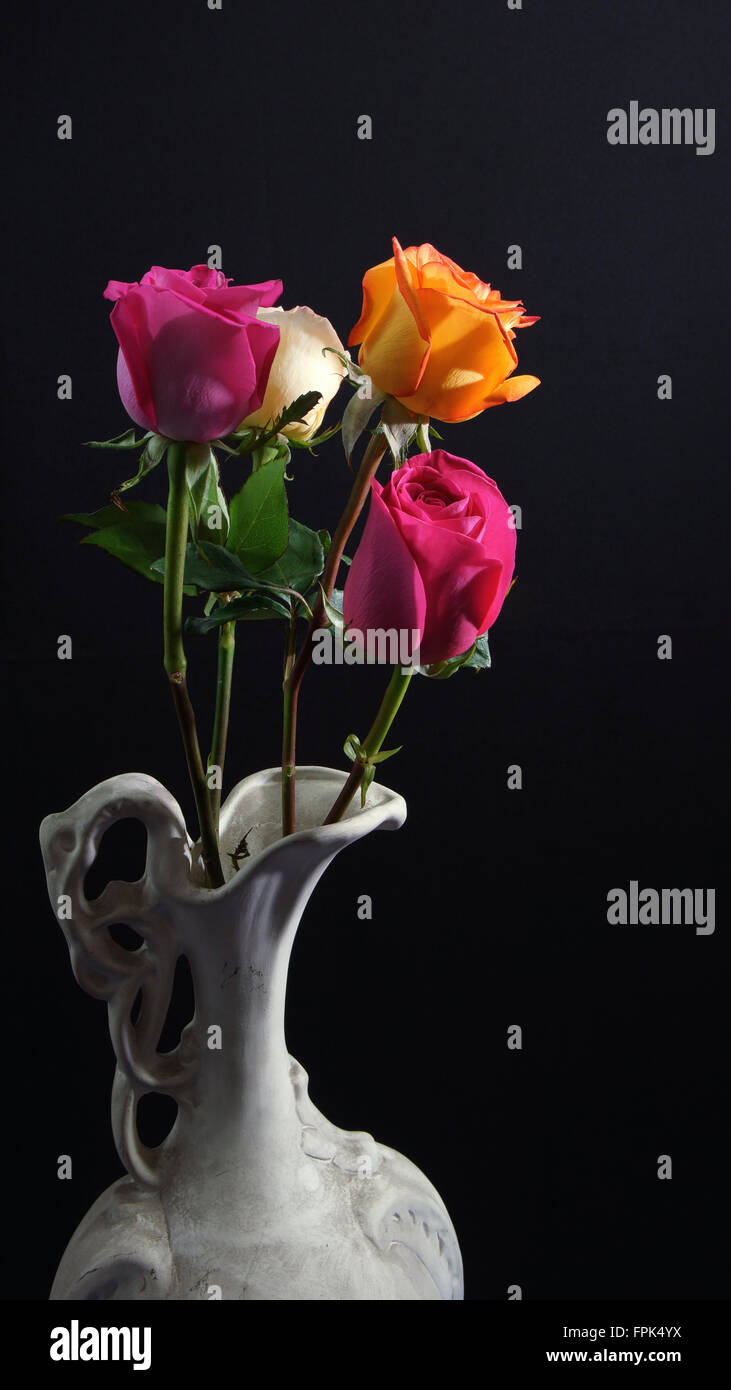 Roses en vase en céramique blanc sur fond sombre Banque D'Images